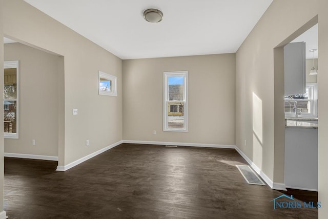 spare room featuring dark wood-style floors, visible vents, and baseboards