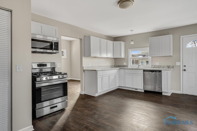 kitchen featuring stainless steel appliances, light countertops, hanging light fixtures, and white cabinetry