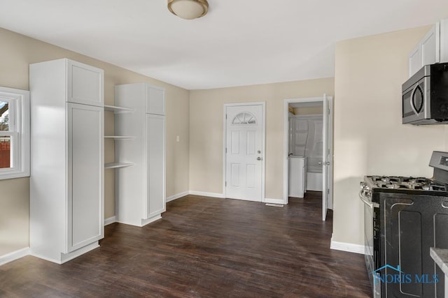 interior space featuring baseboards, stainless steel appliances, dark wood finished floors, and white cabinets