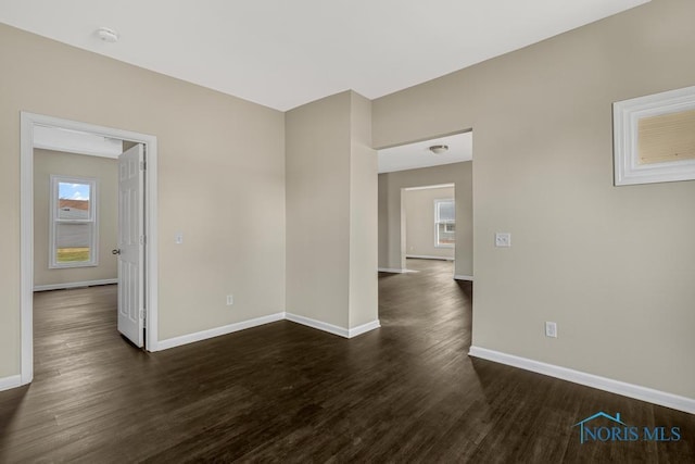 spare room with dark wood-type flooring and baseboards