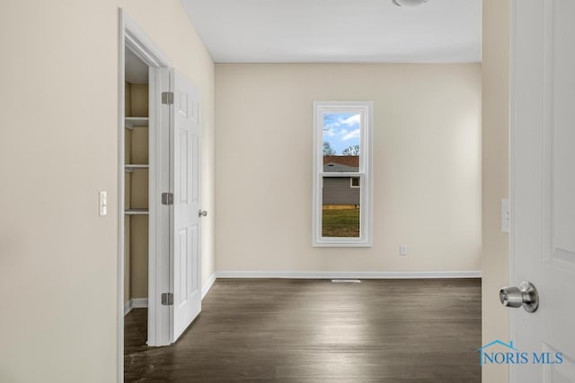 spare room with dark wood-style flooring and baseboards