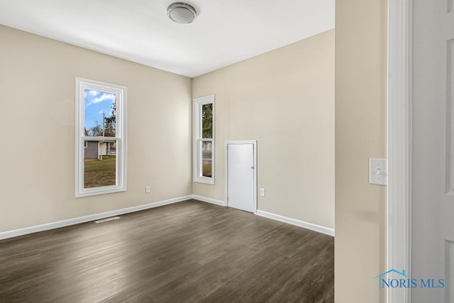 empty room featuring baseboards and dark wood-style flooring