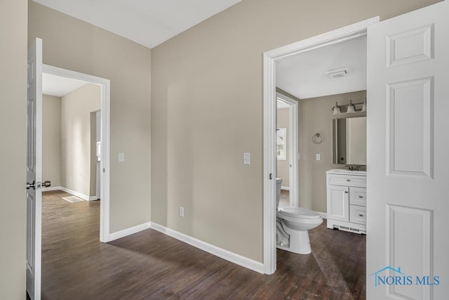 half bath featuring visible vents, toilet, vanity, wood finished floors, and baseboards