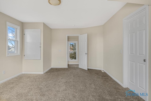 carpeted spare room featuring baseboards