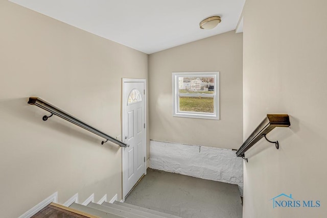 stairway featuring concrete flooring and vaulted ceiling