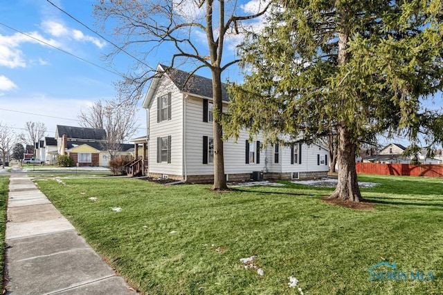 view of side of home with central AC, a lawn, and fence