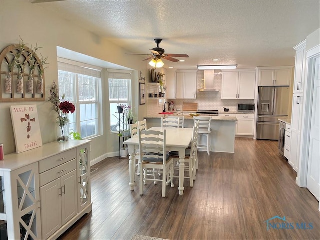 dining space featuring a textured ceiling, ceiling fan, dark wood-type flooring, and baseboards