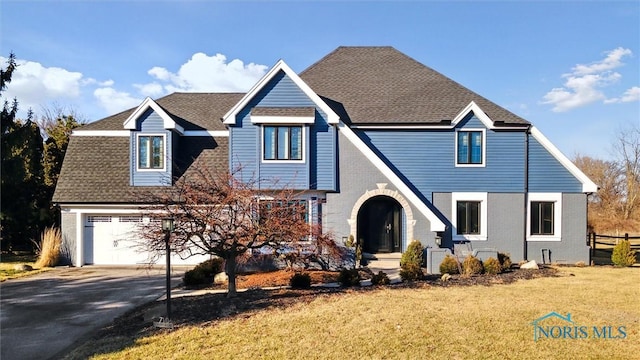 view of front of home featuring aphalt driveway, brick siding, a front lawn, and a shingled roof