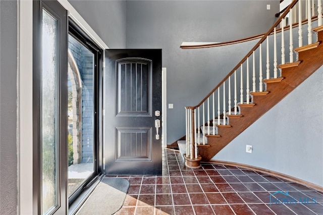 tiled foyer entrance with baseboards and stairs