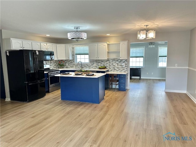 kitchen featuring a center island, decorative light fixtures, light countertops, white cabinetry, and black appliances