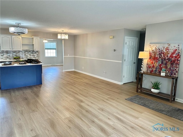 kitchen with hanging light fixtures, tasteful backsplash, light wood-type flooring, and white cabinetry