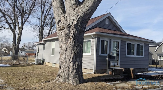 view of side of home featuring entry steps, a shingled roof, and fence