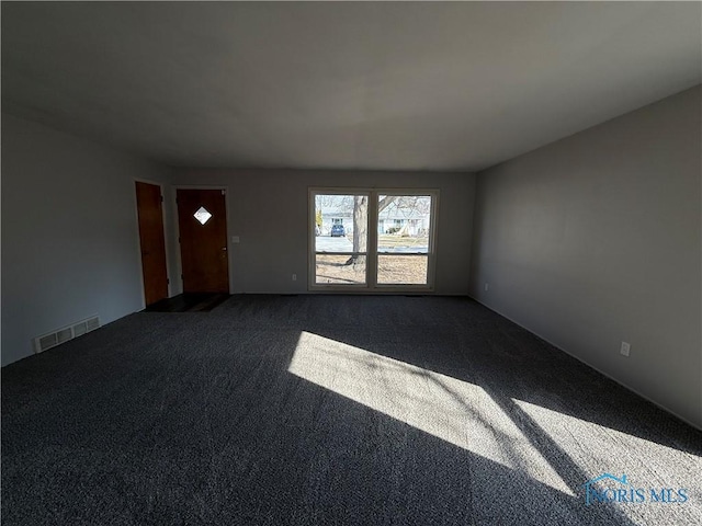 empty room featuring dark colored carpet and visible vents