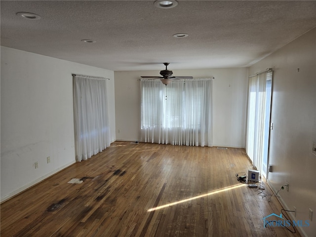 unfurnished room featuring a textured ceiling, baseboards, and wood finished floors