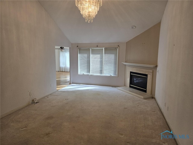 unfurnished living room featuring high vaulted ceiling, light carpet, a high end fireplace, baseboards, and an inviting chandelier