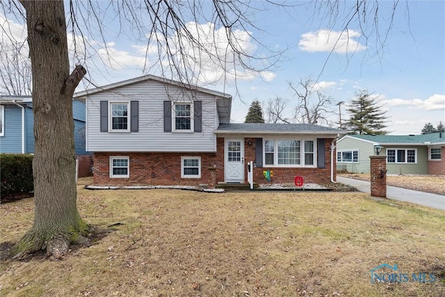 tri-level home featuring brick siding and a front lawn