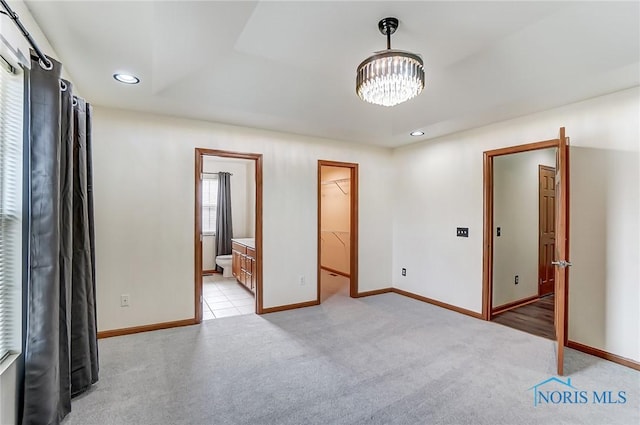 unfurnished bedroom with recessed lighting, light colored carpet, baseboards, a spacious closet, and an inviting chandelier