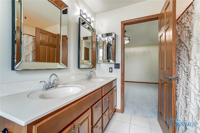 full bath with double vanity, tile patterned flooring, a sink, and baseboards