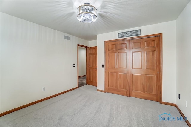 unfurnished bedroom with light carpet, baseboards, visible vents, and a closet