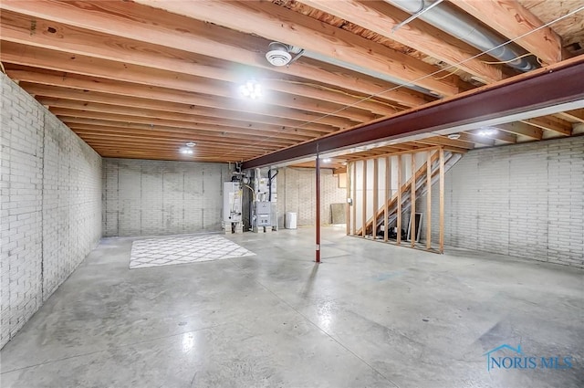 unfinished below grade area featuring gas water heater, brick wall, and heating unit