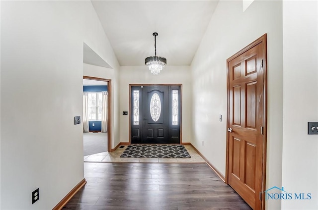 entryway with lofted ceiling, baseboards, a chandelier, and dark wood-style flooring