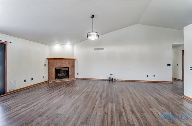 unfurnished living room featuring a fireplace, light wood finished floors, visible vents, vaulted ceiling, and baseboards