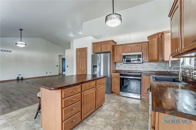 kitchen with dark countertops, appliances with stainless steel finishes, hanging light fixtures, and a center island