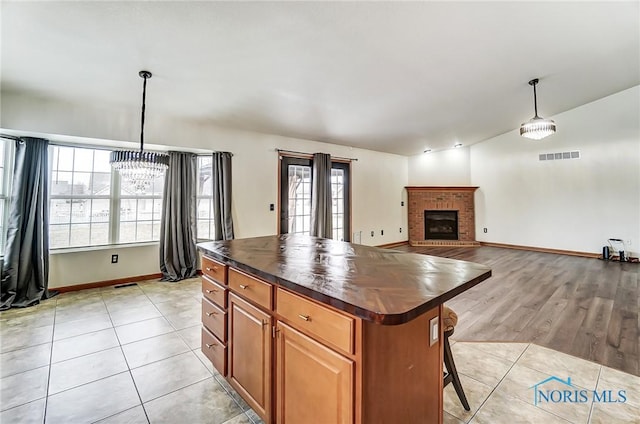 kitchen featuring visible vents, a kitchen island, open floor plan, decorative light fixtures, and light tile patterned flooring