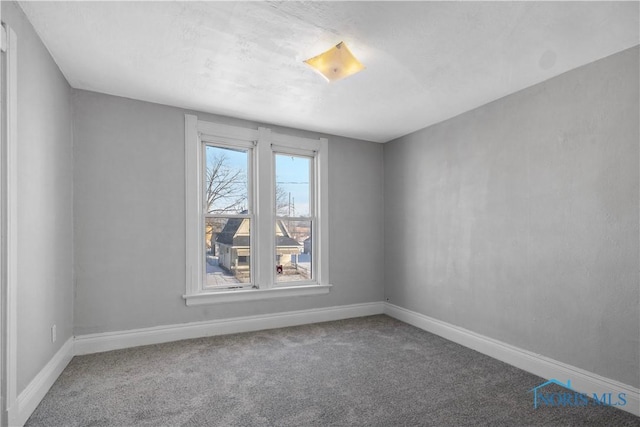 carpeted spare room featuring baseboards