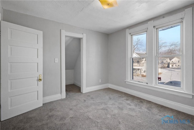 empty room featuring light carpet, a textured ceiling, and baseboards