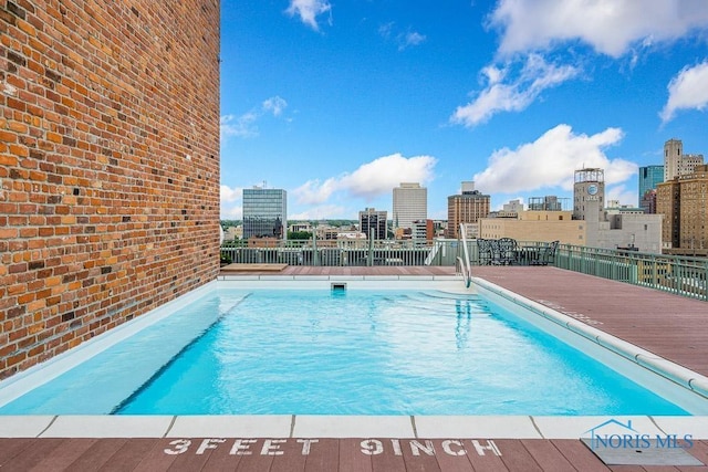 view of swimming pool featuring a view of city and fence