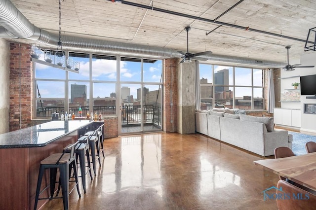 interior space with a view of city, a ceiling fan, finished concrete flooring, and a healthy amount of sunlight