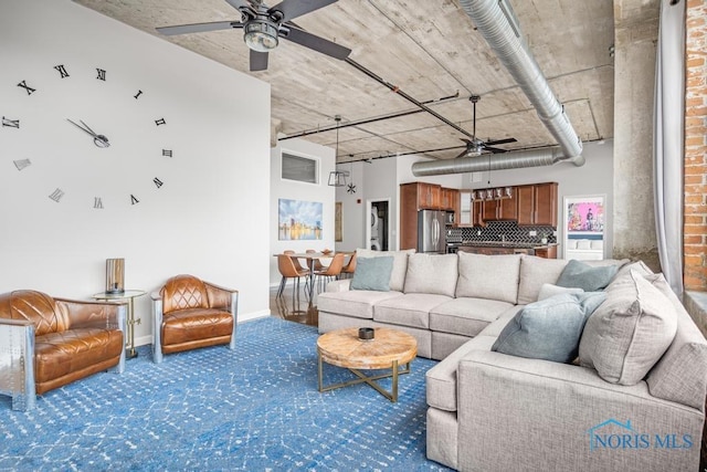 carpeted living room with ceiling fan and baseboards