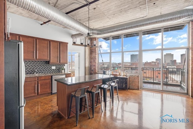 kitchen featuring a center island, a city view, finished concrete flooring, stainless steel appliances, and decorative backsplash