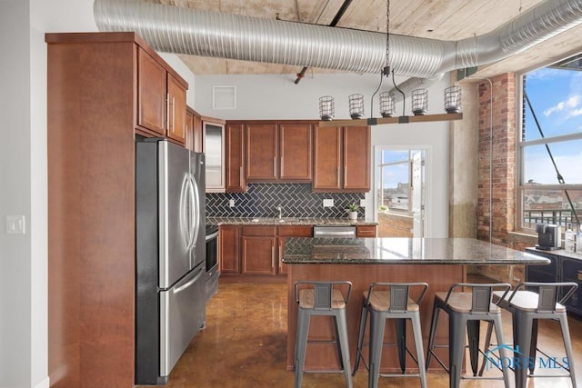 kitchen featuring stainless steel appliances, a breakfast bar, visible vents, backsplash, and dark stone countertops