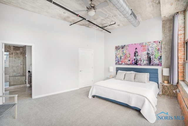 carpeted bedroom with a ceiling fan, connected bathroom, a towering ceiling, and baseboards