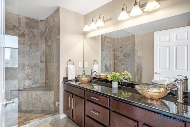 bathroom featuring a tile shower, a sink, and double vanity