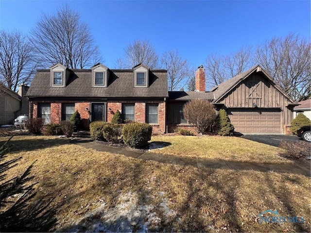 view of front of house with a front yard, brick siding, driveway, and an attached garage