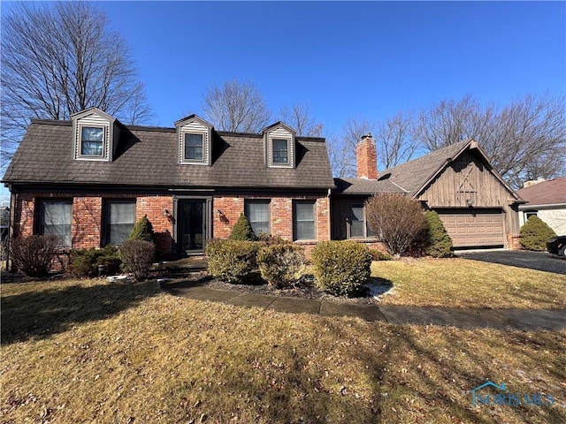 view of front facade with aphalt driveway, brick siding, a shingled roof, an attached garage, and a front yard