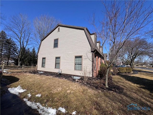 view of side of property with fence and a gambrel roof