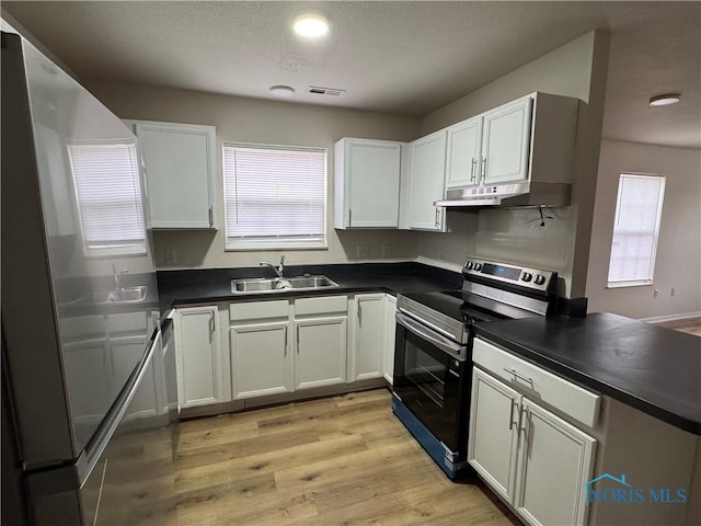 kitchen featuring dark countertops, electric range, white cabinets, and a sink