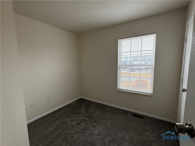 unfurnished room featuring visible vents, dark carpet, and baseboards