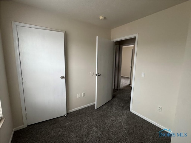 unfurnished bedroom with baseboards and dark colored carpet