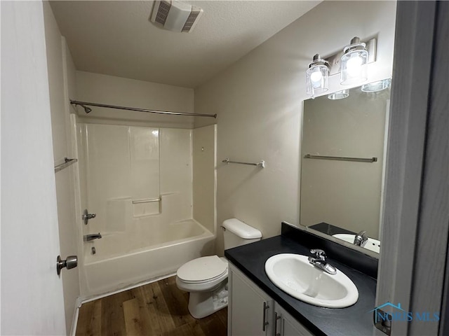 bathroom featuring toilet, wood finished floors, vanity, visible vents, and  shower combination