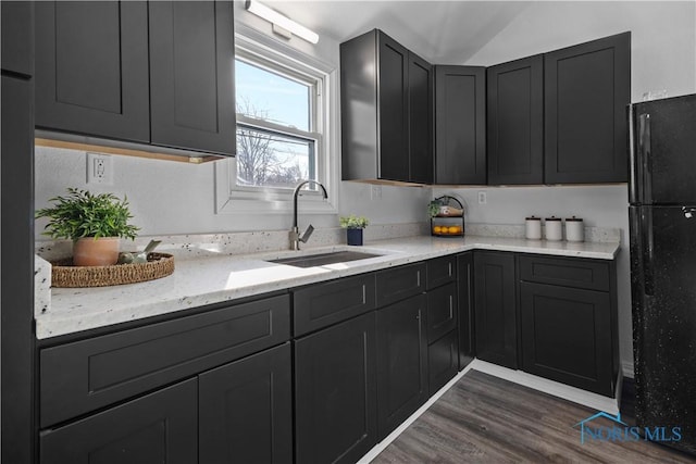 kitchen featuring dark wood-type flooring, a sink, freestanding refrigerator, and dark cabinets