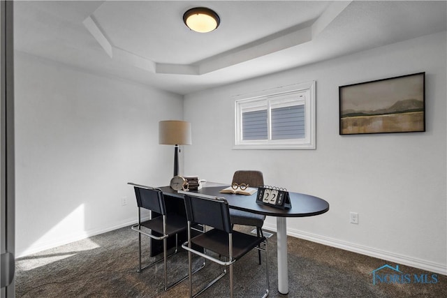 office area featuring baseboards, a tray ceiling, and dark colored carpet