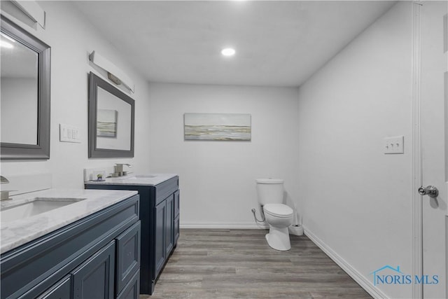 full bathroom with toilet, baseboards, a sink, and wood finished floors