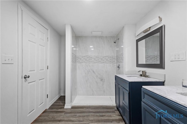 bathroom featuring two vanities, a sink, a shower stall, and wood finished floors