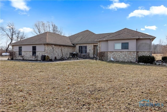 single story home featuring stone siding, a shingled roof, and a front yard