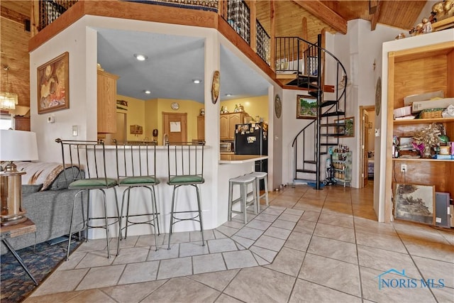 kitchen featuring a breakfast bar area, light tile patterned floors, freestanding refrigerator, high vaulted ceiling, and wooden ceiling